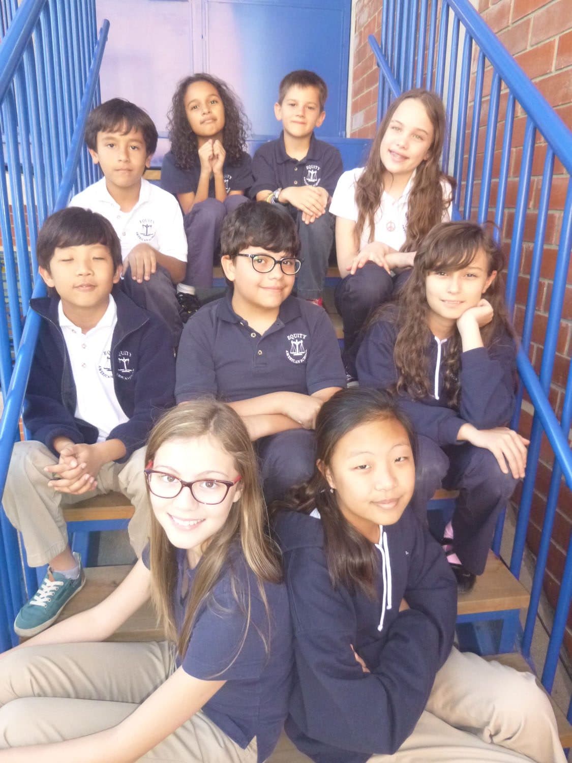 Equity American School students seated together on the school stairs